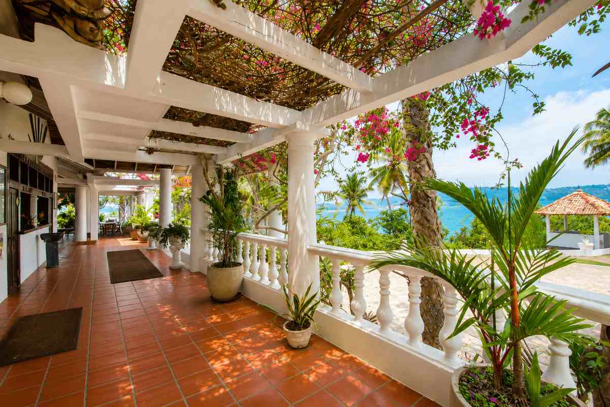 Heritage verandah at Closenberg Hotel with white columns, terracotta tiles and bougainvillea overlooking the bay