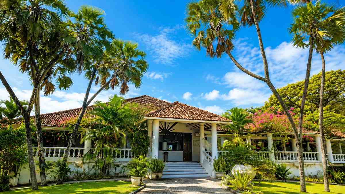 Closenberg Hotel colonial estate facade framed by palms and bougainvillea